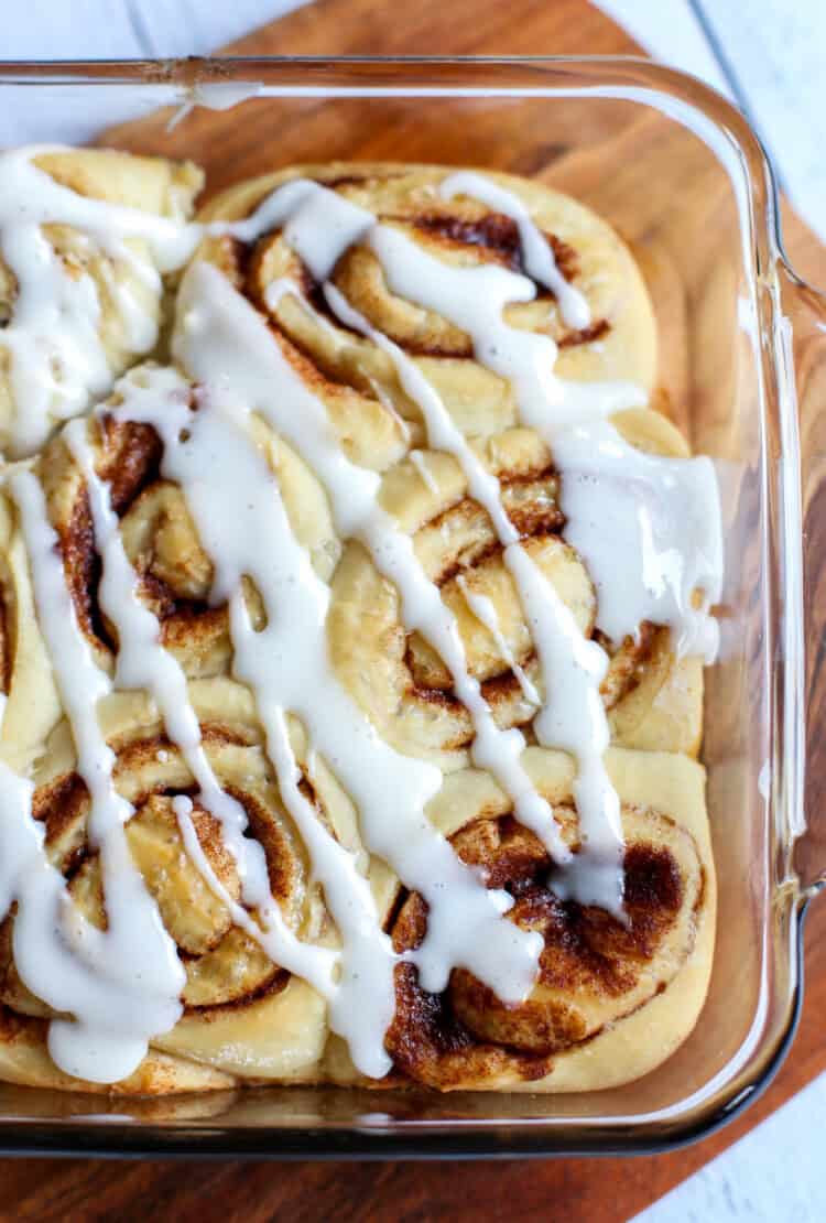 Cinnamon rolls in a glass baking dish with icing drizzled over top.