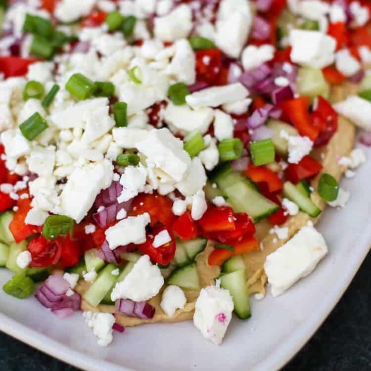 Layered Greek dip on a white platter.