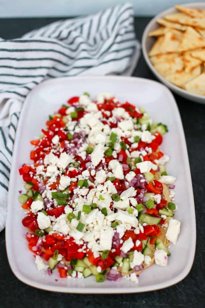 Greek Dip on a white platter with pita chips in the background 