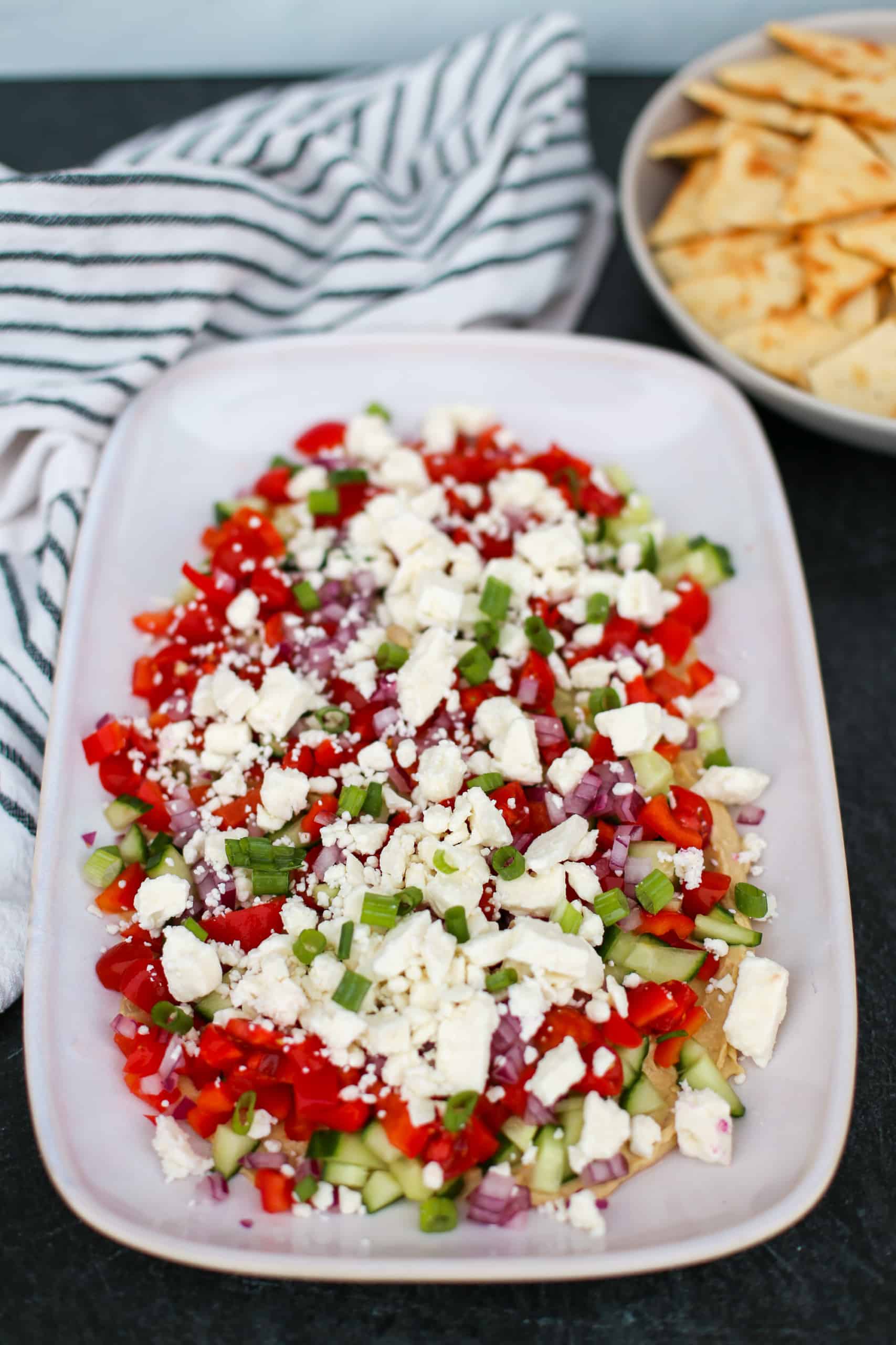 Greek Dip on a white platter with pita chips in the background.