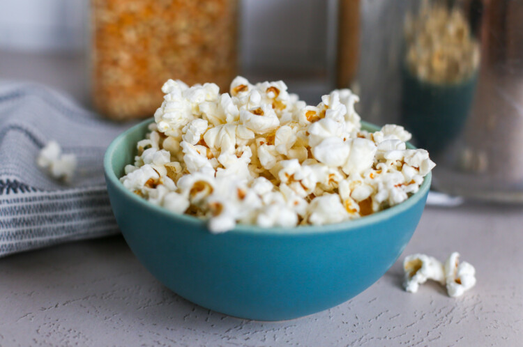 Homemade popcorn overflowing in a blue bowl.
