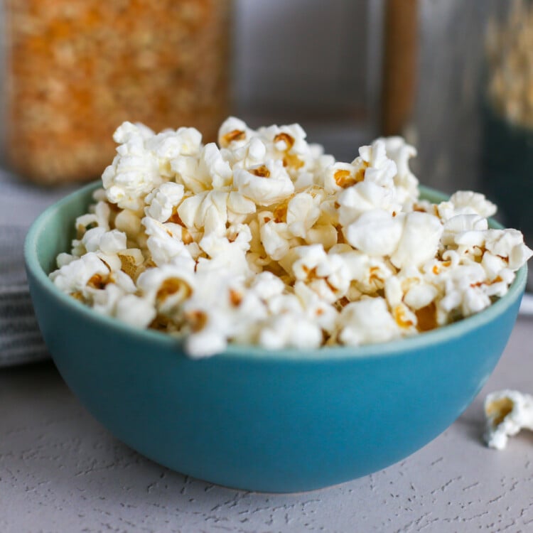 Homemade popcorn overflowing in a blue bowl.