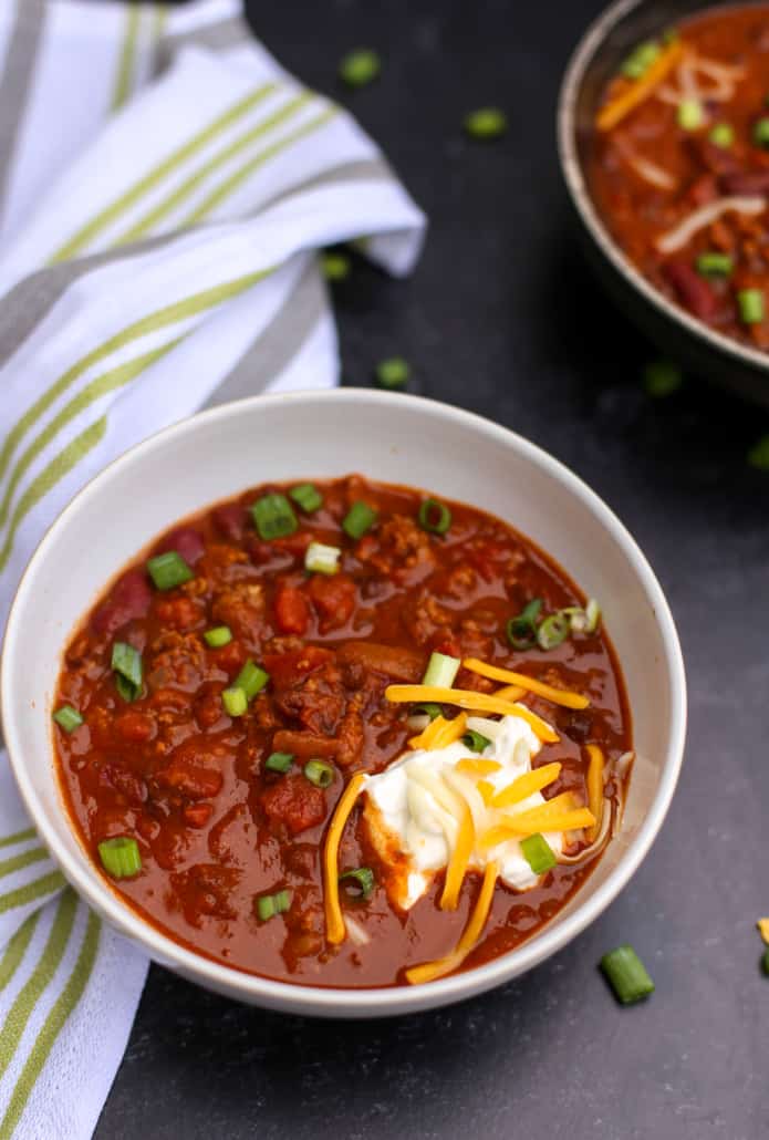 Stovetop chili in a white bowl with toppings 