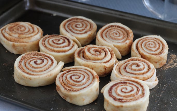 Cinnamon rolls on a baking pan ready to be baked.
