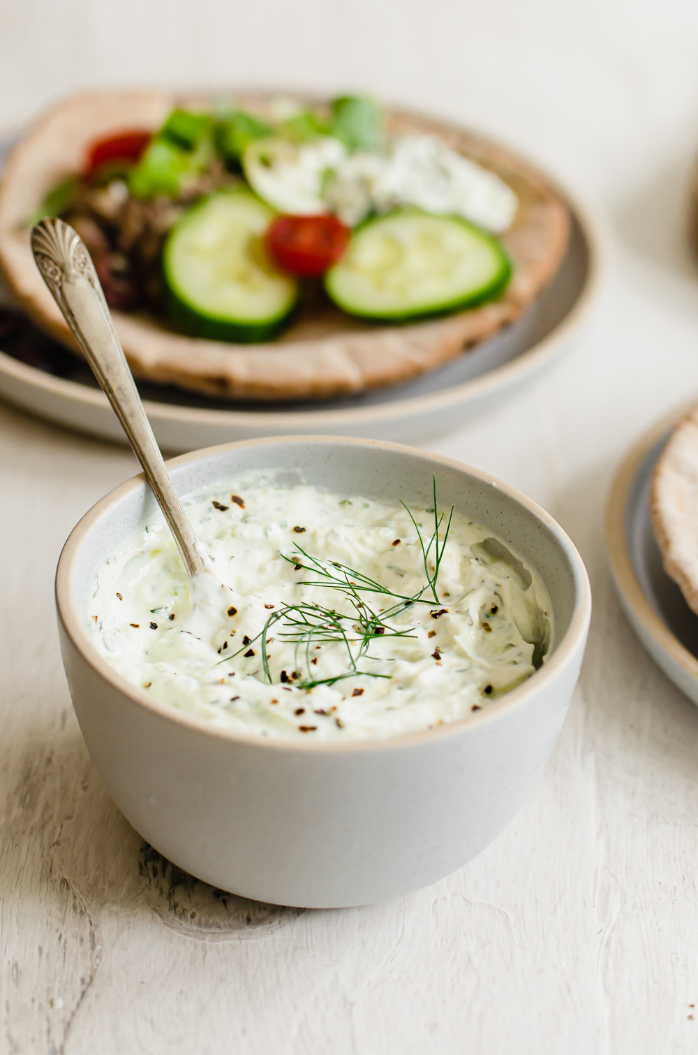 Easy tzatziki sauce in a white bowl with fresh dill on top.
