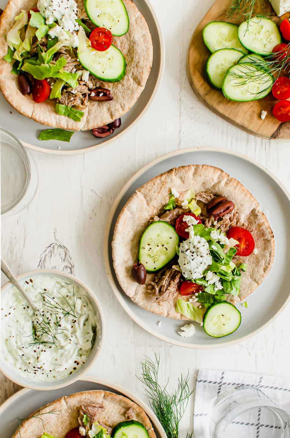 Greek pork pitas with tzatziki, olives, tomatoes, lettuce, and cucumbers.