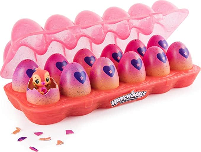 A 12-pack pink egg carton full of Hatchimal eggs with one cracked open and a Hatchimal peeking out.