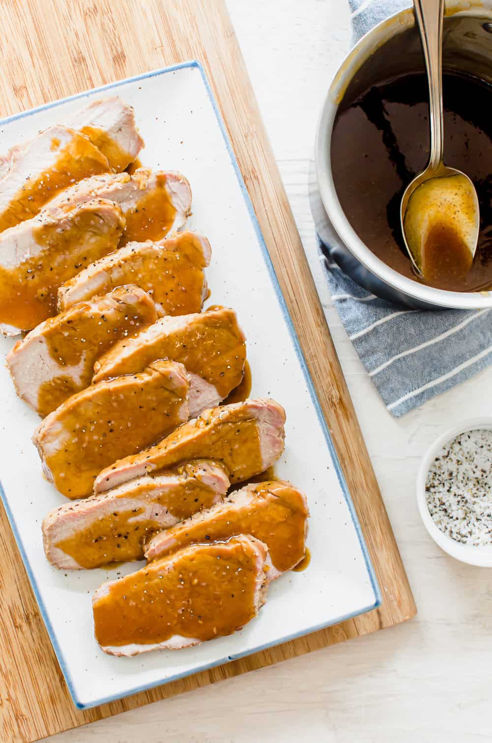 Cooked pork loin on a platter sliced with maple glaze drizzled over the top.