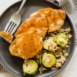 Maple glazed pork sliced on a plate with Brussels sprouts and rice.