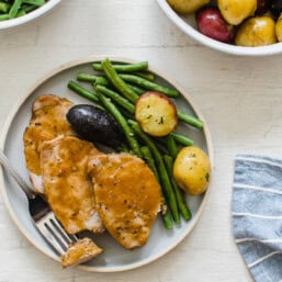 Pork Loin slices with maple glaze on a plate with green beans and baby potatoes.
