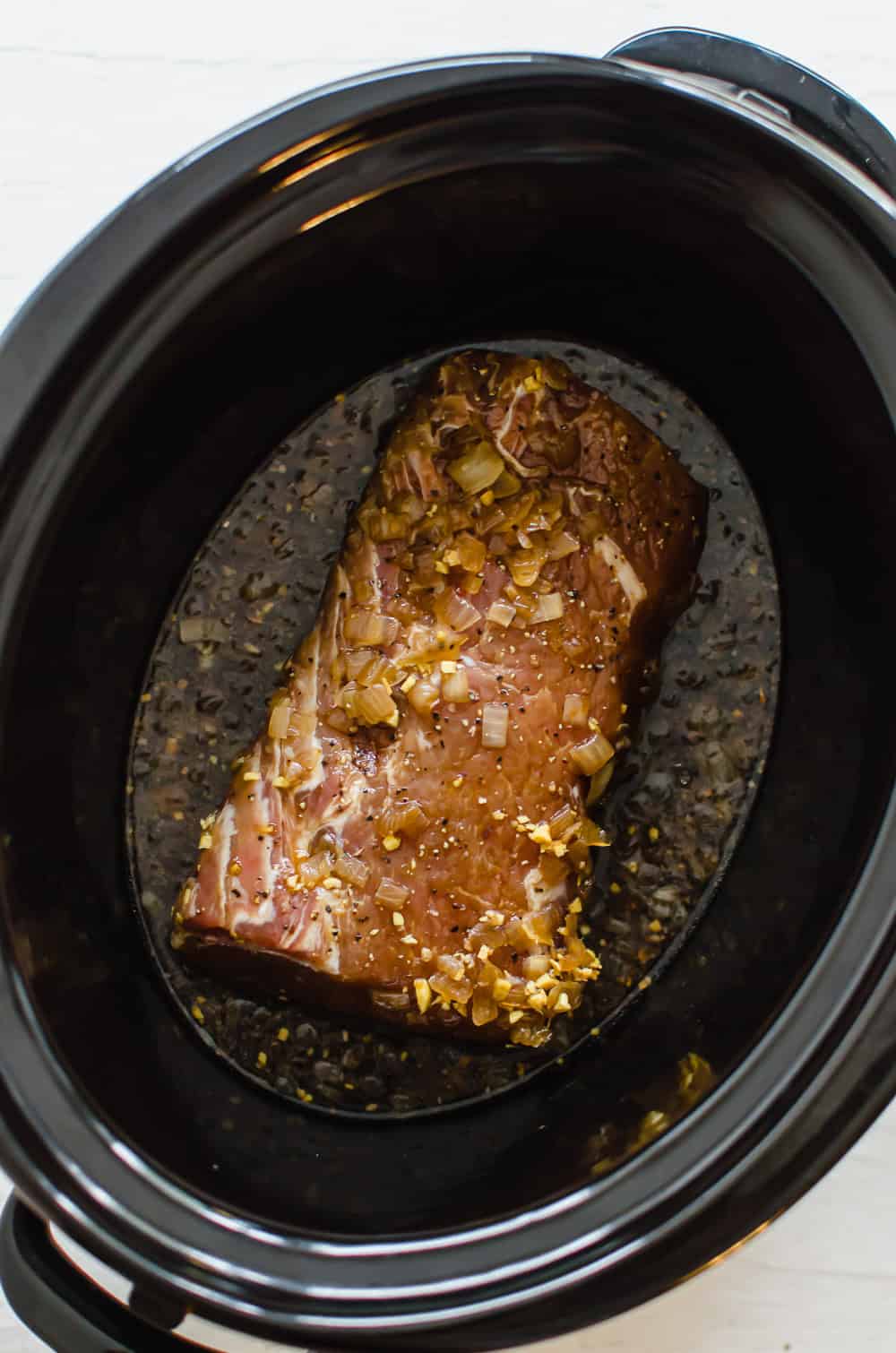 A pork loin in a slow cooker with marinade.