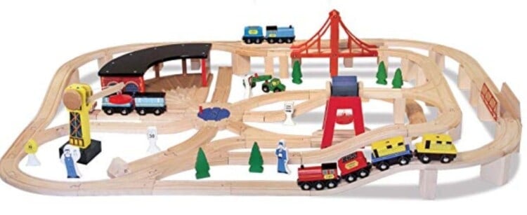 Melissa and Doug wooden train set all set up with trains on the tracks and details like wooden trees sitting around the track.