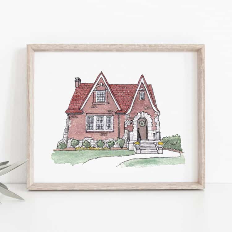 A framed watercolor painting of a red brick house with a darker red roof.