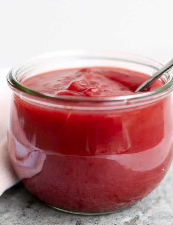 Small jar of cranberry applesauce with a spoon in it.