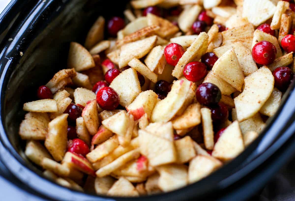 Ingredients mixed together in a crockpot to make apple cranberry sauce.