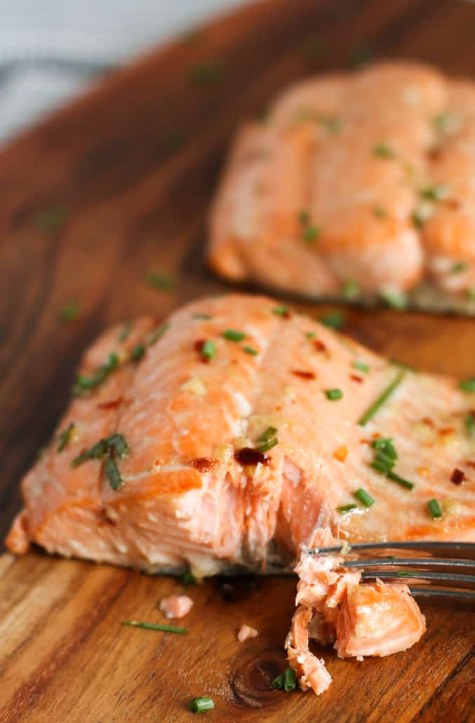 baked asian salmon filets on a wooden chopping block, with a bite taken out of one filet