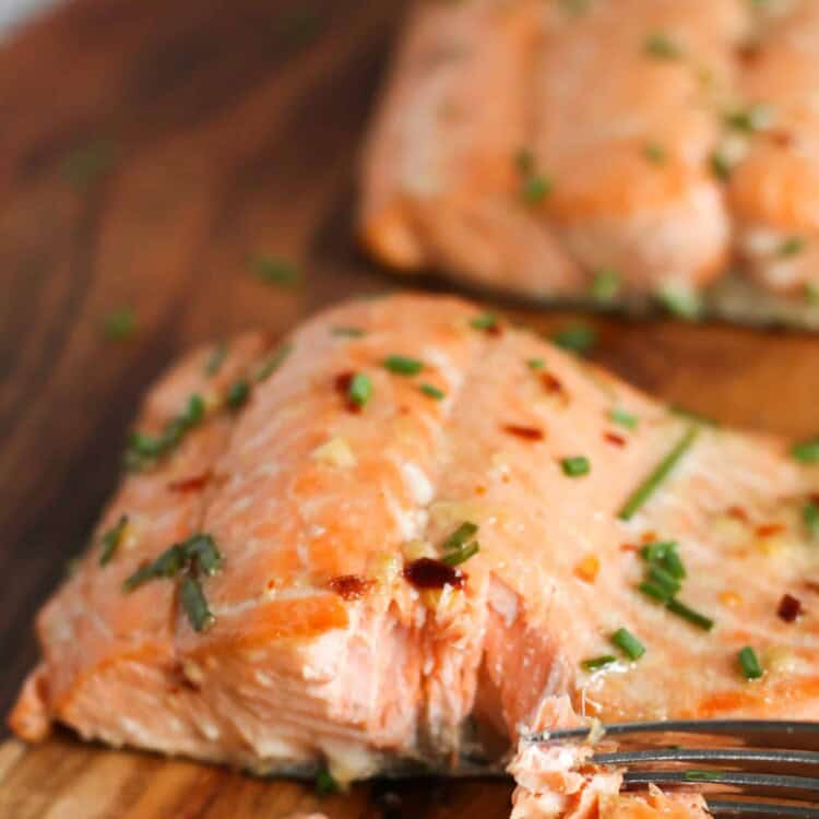 Asian Salmon with chopped chives on top served on a wooden platter.