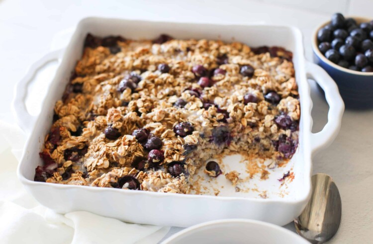 Blueberry baked oatmeal in a white baking dish with some scooped out