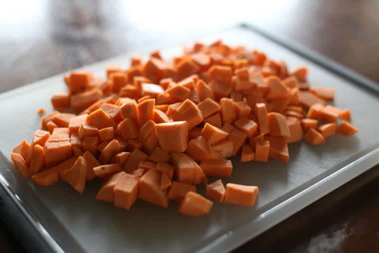 A pile of diced sweet potatoes on a cutting board. 
