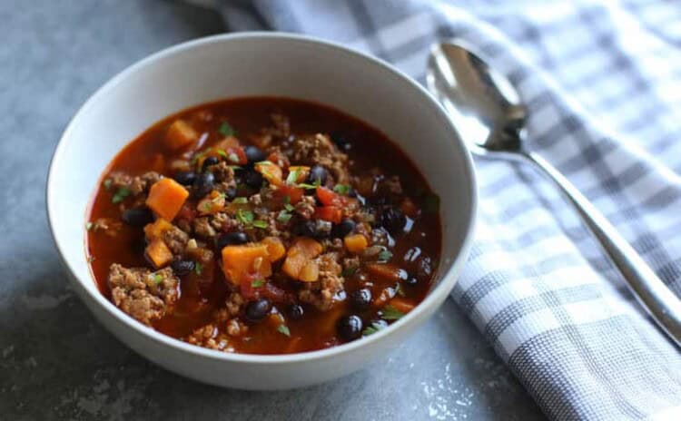 Bowl of turkey chili with a cloth napkin and spoon on the side.