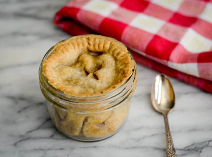 Pie in a mini mason jar ready to eat with a spoon next to it.