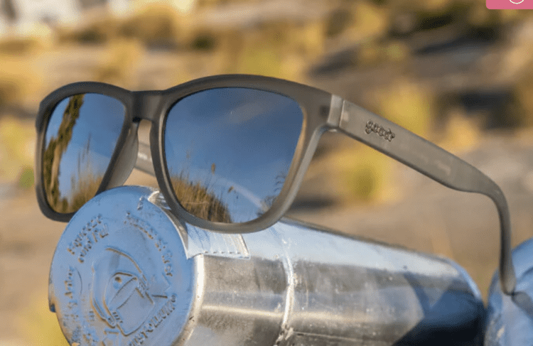 A pair of goodr sunglasses sitting on a metal water bottle.