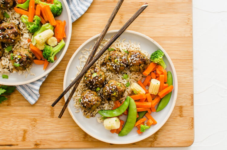 overhead shot of asian meatballs on a plate with stir fry veggies as a side and chop sticks laying on the plate