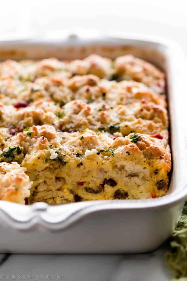 Biscuit breakfast casserole in a white baking dish with a serving taken out.