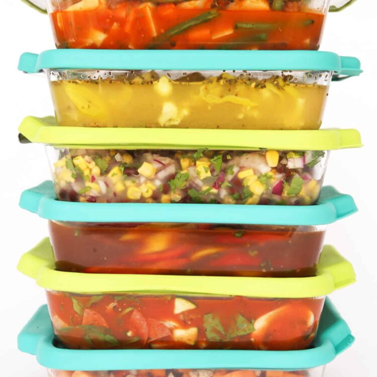 A stack of colorful freezer meals in glass dishes with lids.