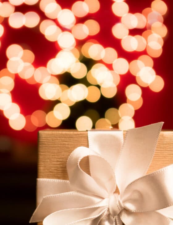 A white wrapped gift with a christmas tree in the background.