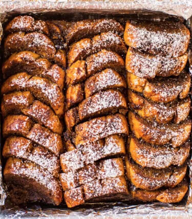 Overnight gingerbread french toast slices lined up and sprinkled with powdered sugar.