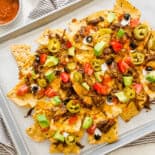 Shredded beef nachos on a sheet pan with toppings added ready to serve.