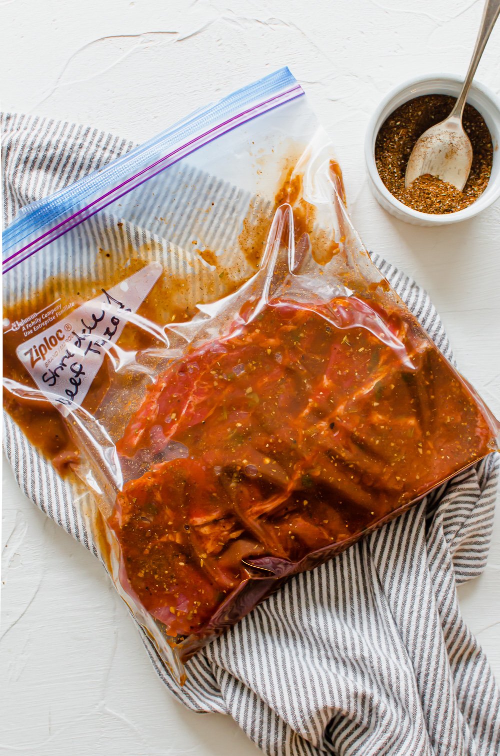 Beef chuck roast in a freezer bag with salsa and seasonings labeled shredded beef tacos.