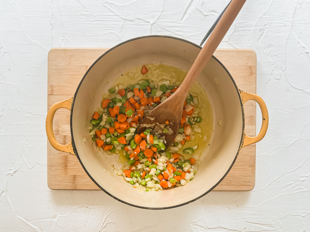 process shot of adding in diced carrots, celery, and onion to saute for soup