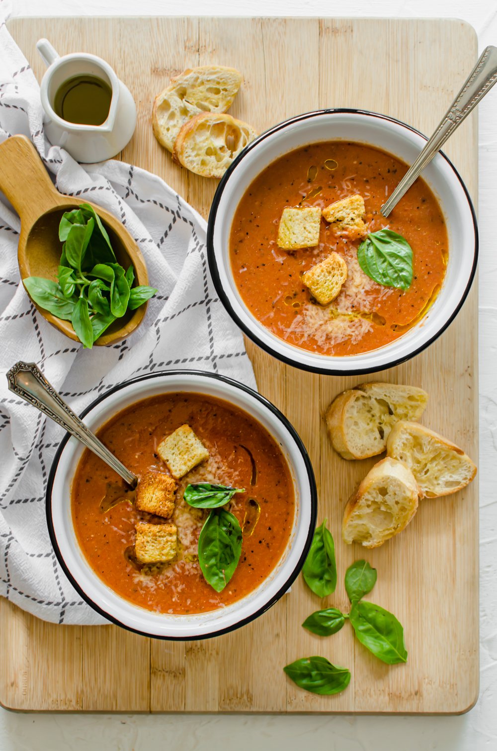 tomato bisque soup in bowls with croutons and fresh basil on top.