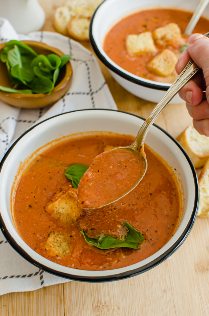 angled shot of tomato bisque soup in a bowl with a spoon