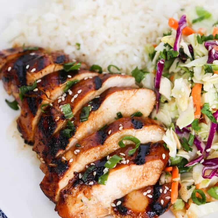 Cooked Asian chicken breast sliced with Asian slaw and rice.