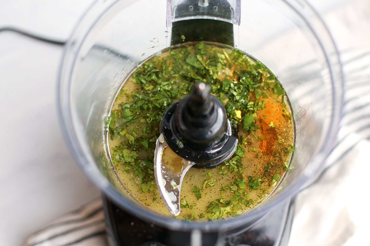 Ingredients for cilantro lime vinaigrette in a food processor ready to be blended together.