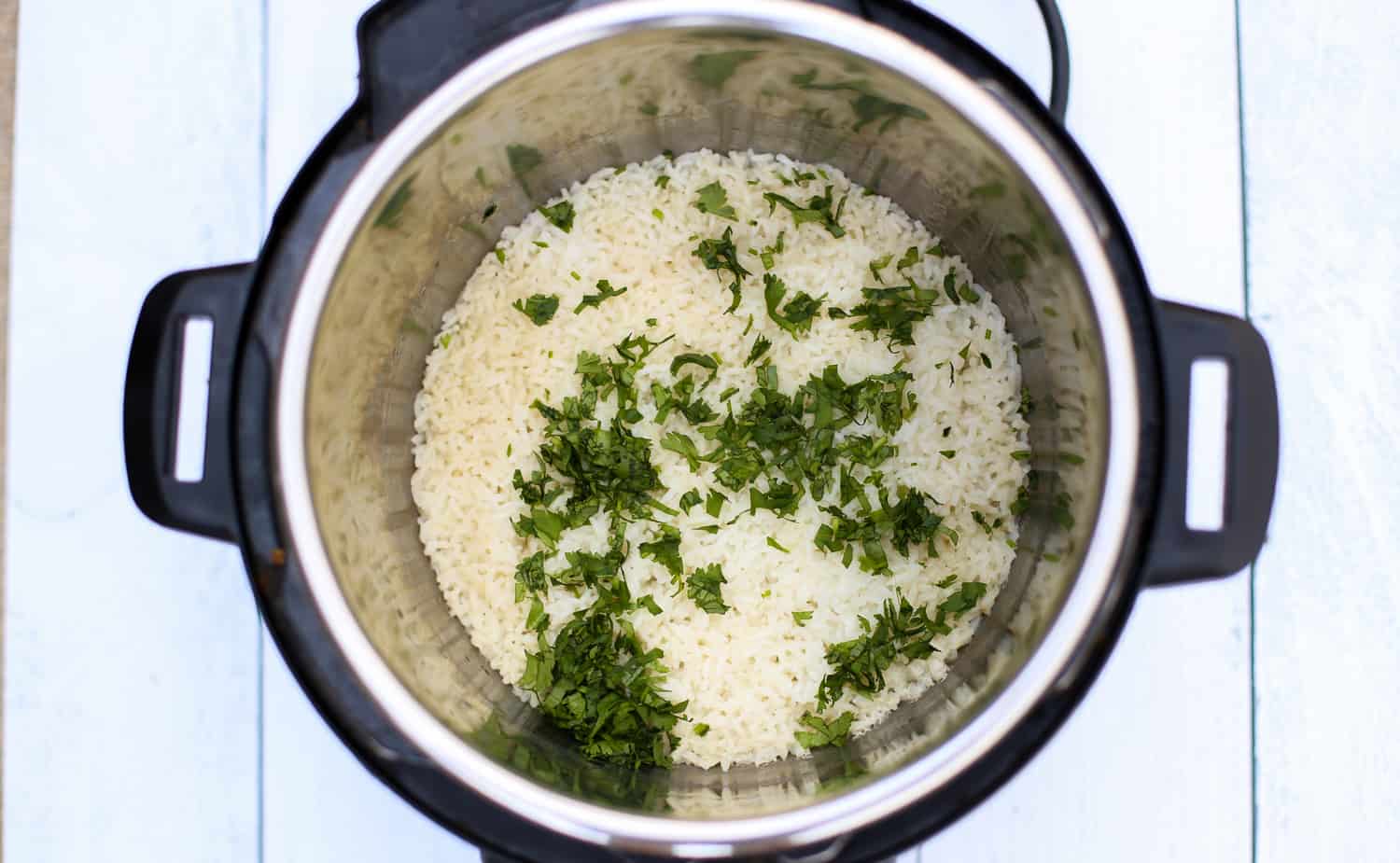 Fully cooked white rice in an instant pot with chopped cilantro on top.