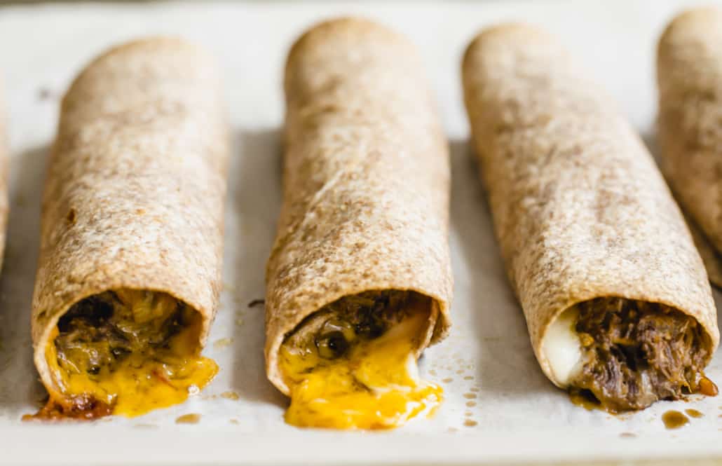 A close up of cooked shredded beef taquitos