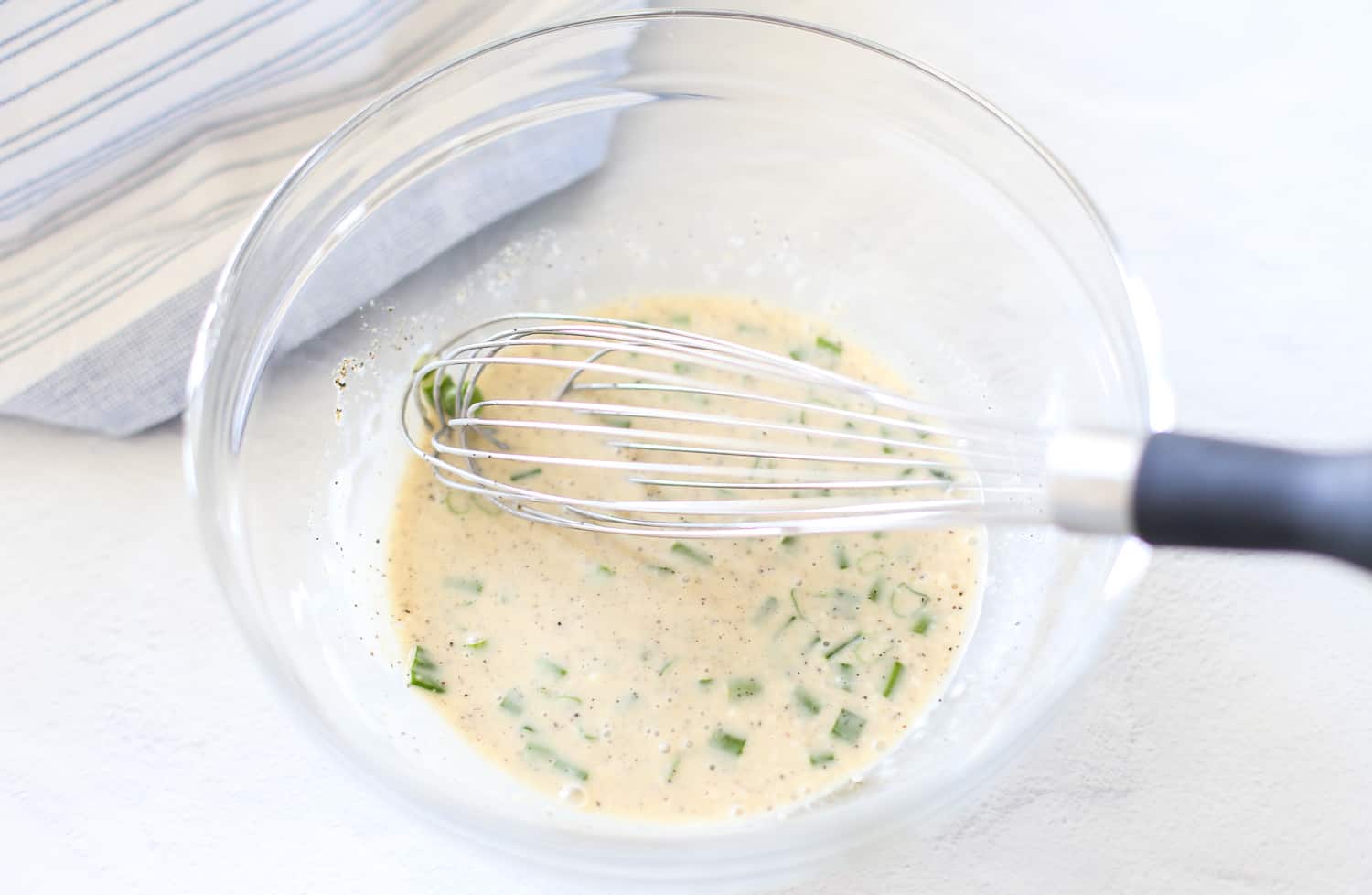 Coleslaw dressing being whisked together in a glass serving bowl.