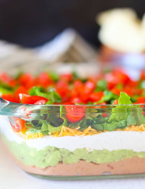 Layered taco dip in a square glass baking dish.