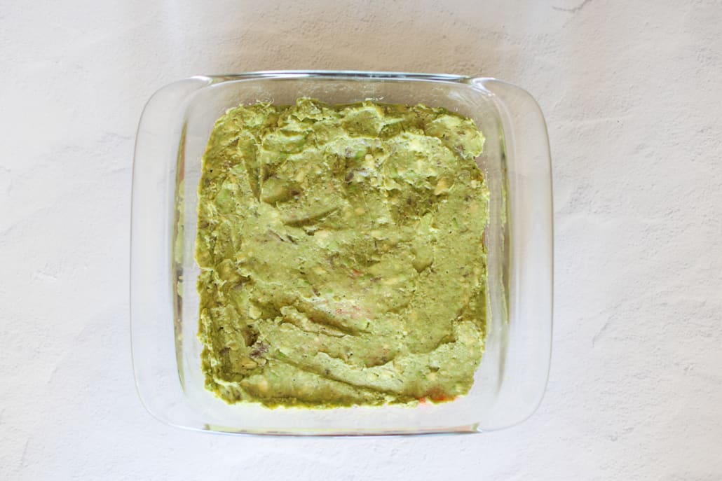 Overhead shot of avocado layer in layered taco dip recipe 