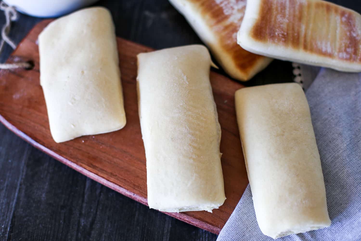 Baked panini bread laid out on a cutting board.