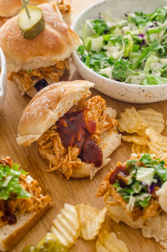 Instant pot BBQ chicken sliders on a wooden cutting board with coleslaw on the side