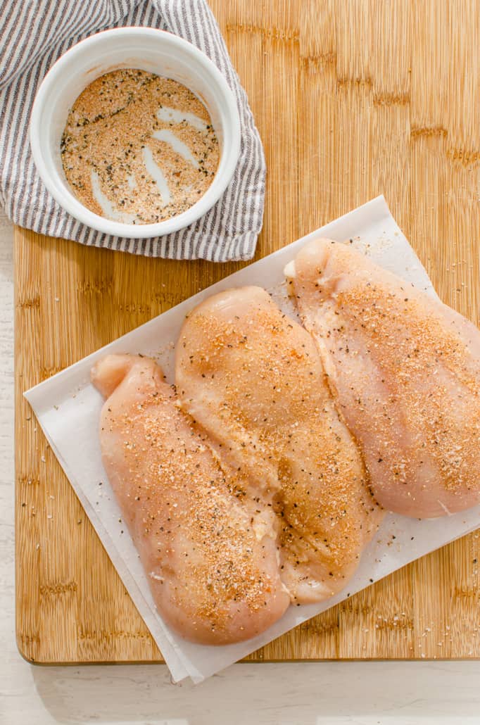 Raw, seasoned chicken on a cutting board