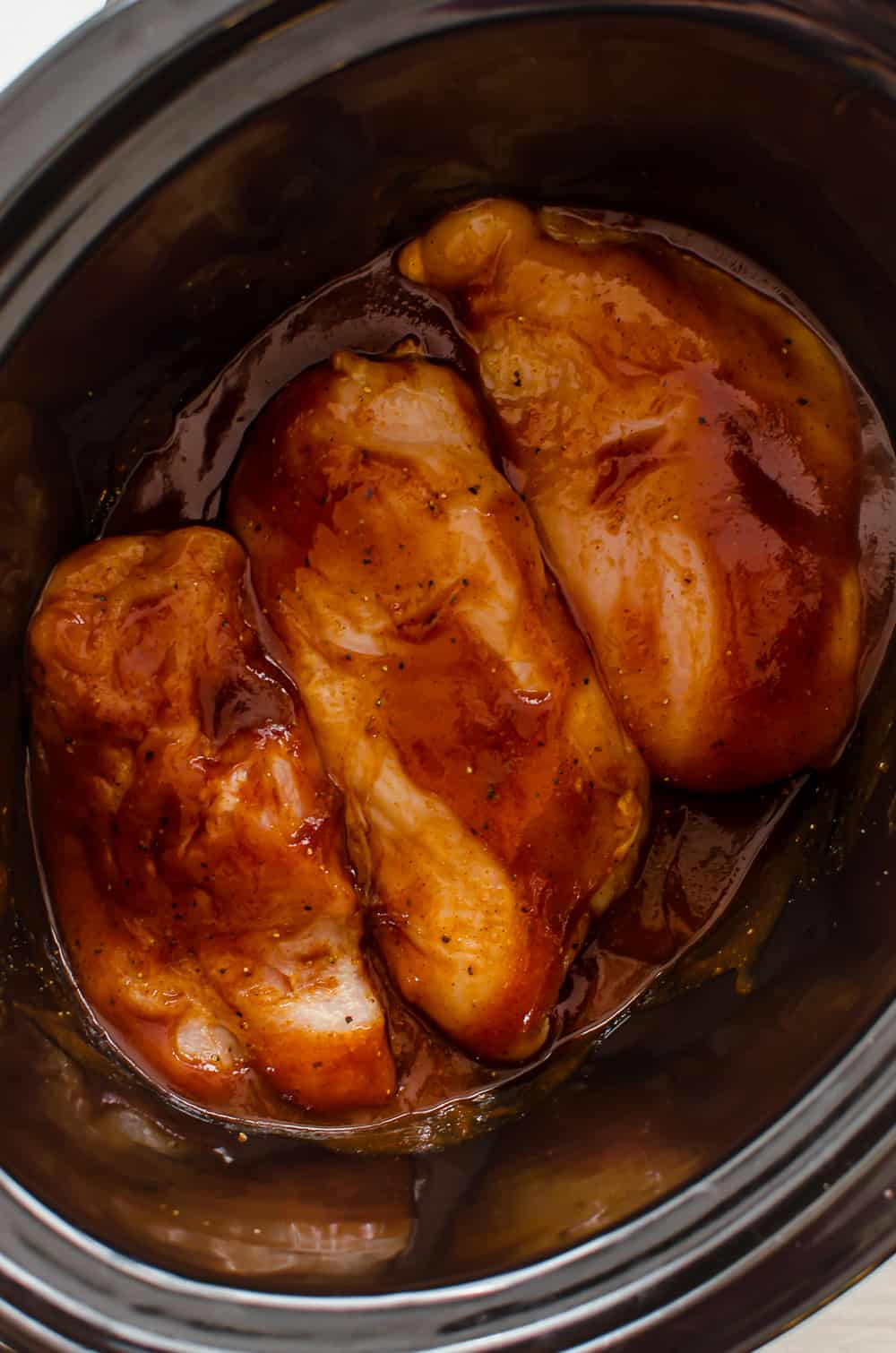 Raw chicken in a slow cooker with BBQ Sauce 