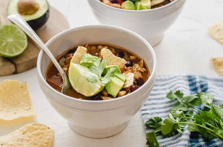 Chicken taco soup in a white bowl with toppings.