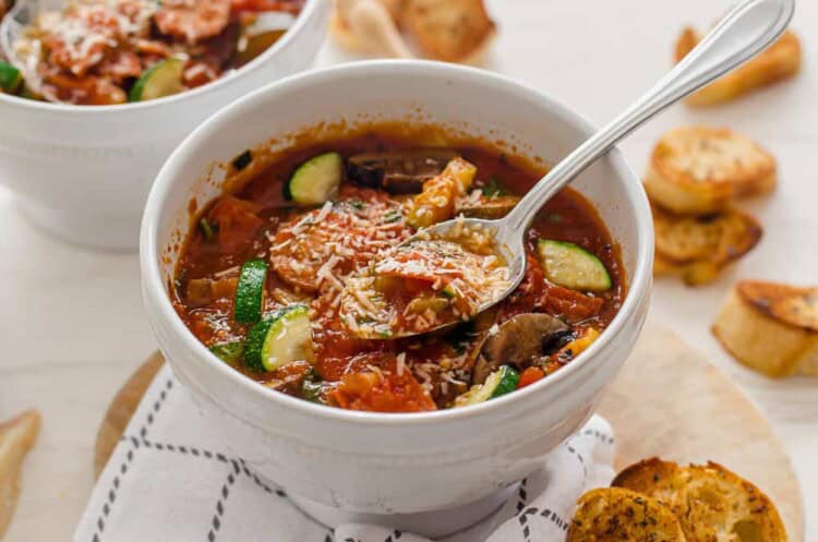 A bowl of pizza soup with shredded Parmesan on top.