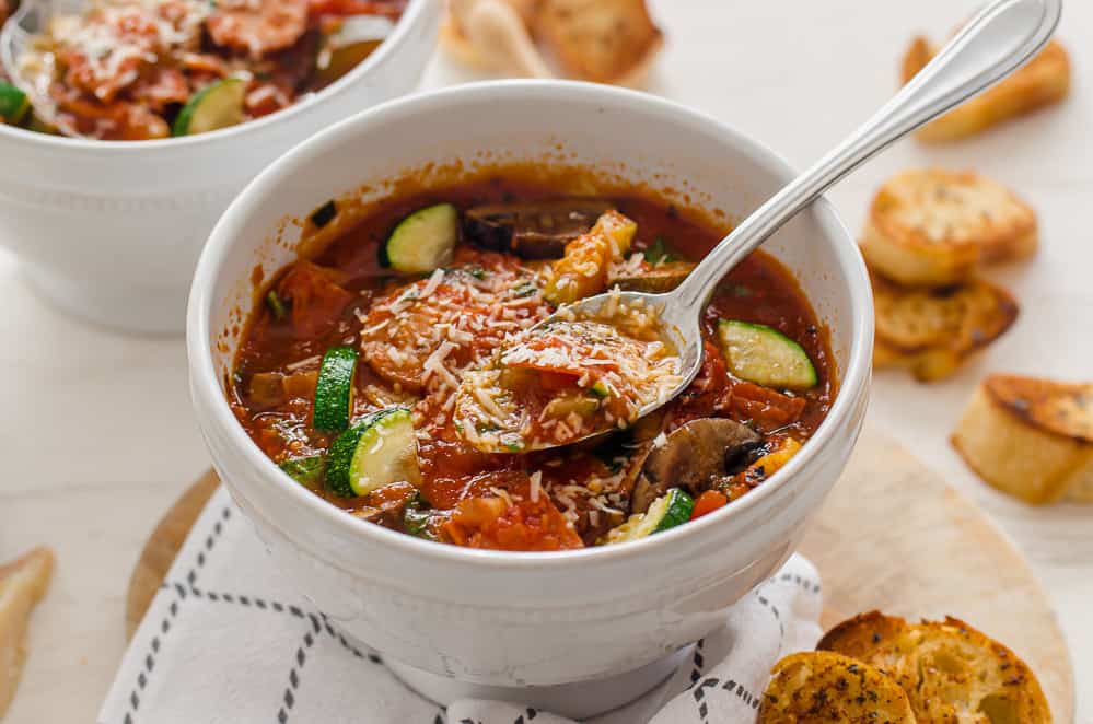 A bowl of pizza soup with shredded Parmesan on top.